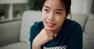 Handheld selective focus shot, Relaxed young woman is sitting on a sofa, enjoying the peace of mind and seems to be thinking about something in a positive mood in living room at home. video