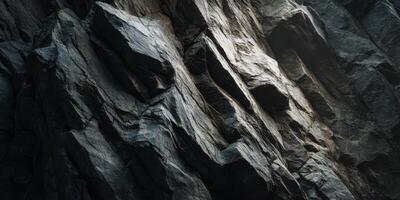 Close up of rugged dark textured rock surface with light photo