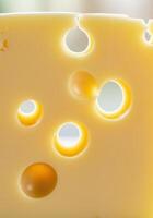 Close up view of a cheese slice with multiple holes in bright yellow tones. photo