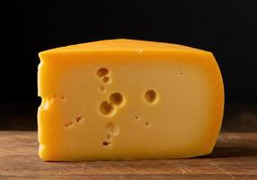 A delightful wedge of cheese with visible holes, presented beautifully on a wooden surface. photo