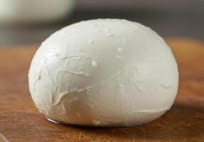 A fresh, juicy ball of mozzarella cheese resting on a wooden cutting board. photo