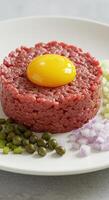A visually appealing beef tartare with a bright yellow egg yolk, ready to be enjoyed. photo