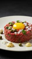 A close up shot of a beautifully arranged beef tartare with egg yolk and capers on a plate. photo
