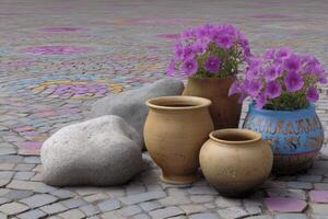 Collection of rustic clay pots and smooth stones arranged on a colorfully painted cobblestone photo