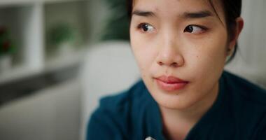 Handheld selective focus shot, Young woman sitting alone on the sofa thinking about life problems with a stressed expression on her face. video