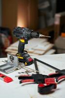 Cordless drill with bits and hand tools on workbench in workshop. Home renovation, construction and repair concept photo
