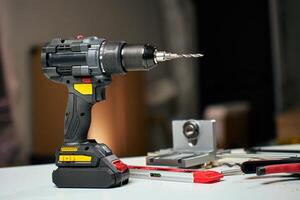 Electric cordless drill with bits and hand tools on workbench in workshop photo