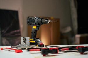 Electric cordless drill with bits and hand tools on workbench in workshop. Home renovation and repair concept photo