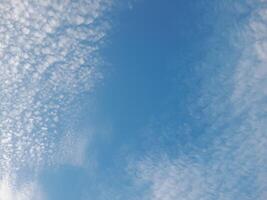 A calm sky filled with scattered white clouds under a clear blue backdrop, creating a peaceful and serene atmosphere. photo