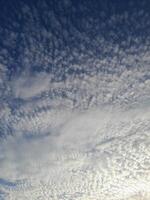 Soft, scattered clouds stretch across a calm blue sky, creating a peaceful and serene morning atmosphere photo