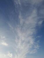 Clear blue sky with soft, wispy clouds creating a calm and peaceful atmosphere, ideal for nature, weather, or relaxation-themed visuals photo