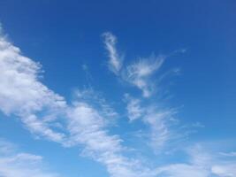 Blue sky with scattered thin white clouds, creating a refreshing and peaceful view of a sunny day. photo