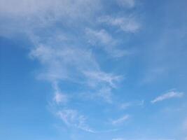 Clear blue sky with soft, scattered white clouds creating a calm and peaceful atmosphere, perfect for nature or weather-themed visuals photo