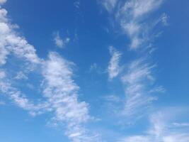 Blue sky with scattered, soft white clouds creating a light, airy, and peaceful daytime scene. photo