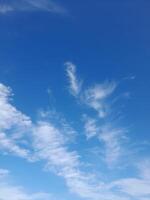 Clear blue sky with soft, wispy clouds scattered gently, creating a calm and peaceful daytime atmosphere. photo