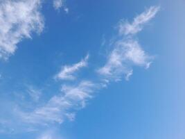 Blue sky with scattered thin white clouds, creating a refreshing and peaceful view of a sunny day photo