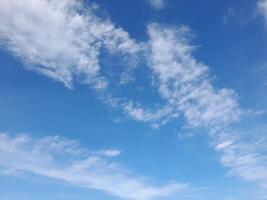 Blue sky with scattered, soft white clouds creating a light, airy, and peaceful daytime scene photo