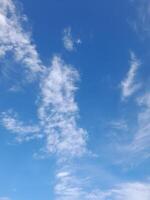 Bright blue sky with scattered, soft white clouds, creating a fresh, airy, and peaceful outdoor atmosphere. photo