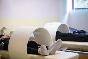 Magnet Therapy Procedure.Patients lying down with legs inside circular magnetic therapy devices during a physiotherapy session. photo