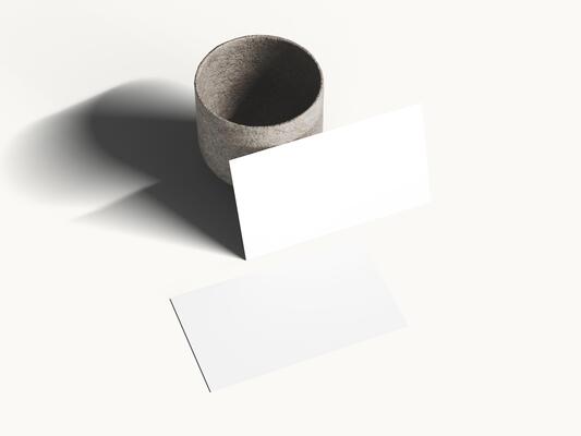 Clean white business card mockup on soft surface with gentle shadow.