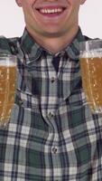 Cheerful man joyfully presenting two frosty beer mugs to the camera video