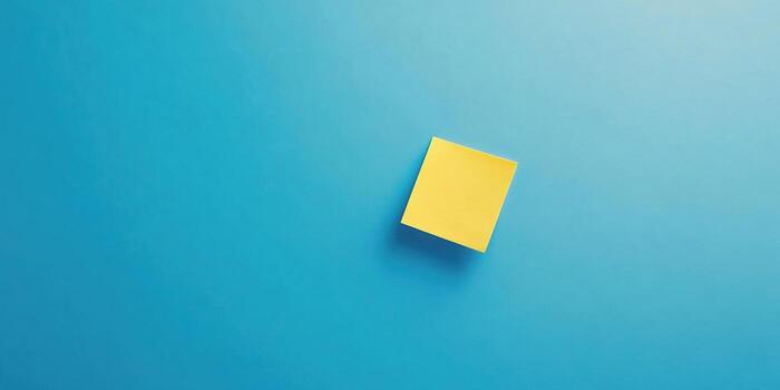Minimalist top down composition of blank yellow sticky note on blue background for office design photo