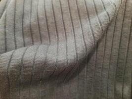 Close-up of a gray ribbed knit fabric with vertical textured lines, creating a soft and stretchy appearance. photo