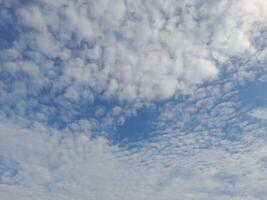 Bright blue sky with scattered white clouds forming soft patterns. A peaceful and serene daytime view, showcasing the beauty of a calm and clear atmosphere. photo