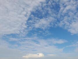 A peaceful sky filled with soft, scattered clouds against a bright blue background. The cloud patterns suggest calm weather and a serene atmosphere. photo