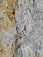 Close-up image of a rough stone surface showing natural textures and earthy tones with visible cracks and patterns formed by weathering. photo