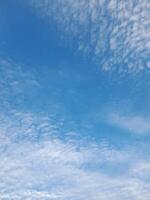 A bright blue sky adorned with soft, scattered white clouds, creating a peaceful atmosphere. photo