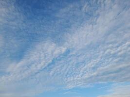Soft, scattered clouds stretch across a calm blue sky, creating a peaceful and serene morning atmosphere. photo