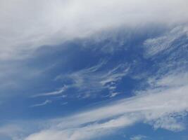 A clear blue sky with wispy white clouds drifting gently, creating a peaceful and refreshing atmosphere. photo