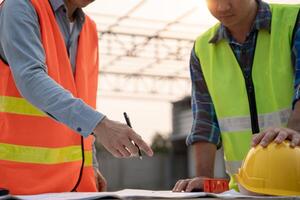 inspector engineer is inspecting construction and quality assurance new house using a blue print. Engineer or architects or contactor work to build the house before handing photo