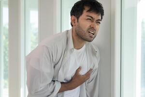 hand hold chest with heart attack, man working hard have chest pain caused by heart disease, leak, dilatation, enlarged coronary heart, press on the chest with a painful expression photo