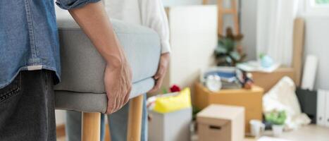 Moving house, relocation. Couple help set sofa and move furniture for new apartment, inside the room was a cardboard box contain personal belongings. move in new apartment or condominium photo