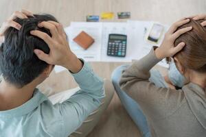 Stress and headache asian couple with large bills or invoices no money to pay to expenses and credit card debt. shortage, Financial problems, mortgage, loan, bankruptcy, bankrupt, poor, empty wallet photo