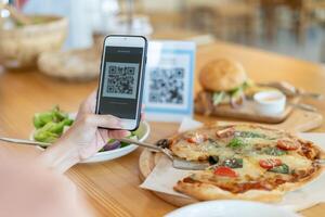 Women use smartphone to scan code for order menu in cafe restaurant with a digital delivery. Choose menu and order accumulate discount. E wallet, technology, pay online, credit card, bank app. photo