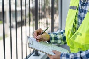 inspector engineer is inspect construction and quality assurance new house using a checklist. Engineers or architects or contactor work to build the house before handing it over to the homeowner photo