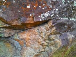 A close-up of natural rock surface with rough texture, erosion marks, and earthy tones, showing the raw features of weathered stone photo