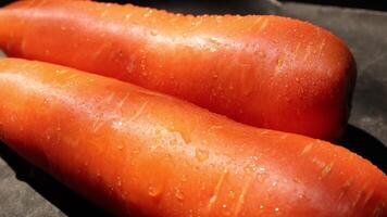 two carrots are sitting on top of a black surface video