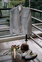 a white jacket, shoes and a flower are on a balcony photo