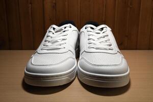 Front view extreme macro photography of brand new white sneakers on yellow wooden shelf photo
