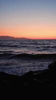 Breaking waves on rocks during beautiful sunset over calm ocean video