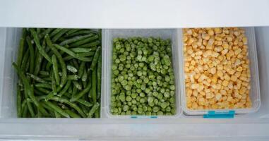 Frozen green beans, peas, and corn preserving freshness in refrigerator photo