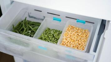 Frozen vegetables preserving freshness in refrigerator drawer. peas, green beans, and corn photo