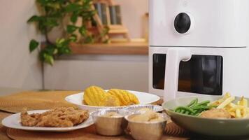 White air fryer displaying various dishes on kitchen table video