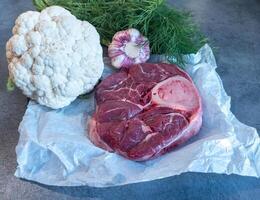 Raw Beef Shank with Bone and Fresh Vegetabl on Parchment Paper photo