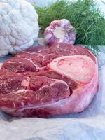 Raw Beef Shank with Bone and Fresh Vegetables on Parchment Paper photo
