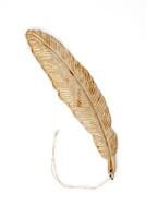 Golden feather-shaped ornament with string, isolated on white background. Elegant decorative object for interior design. photo
